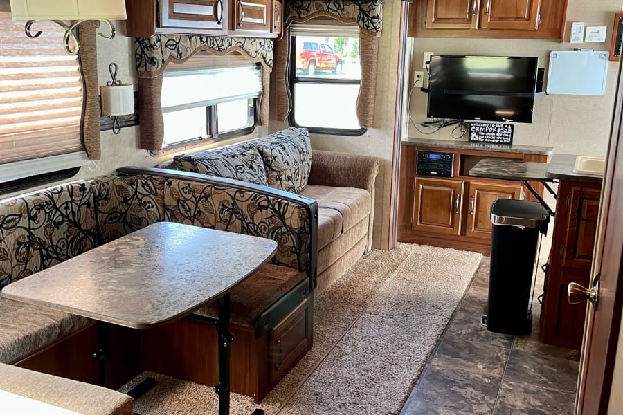 Explore this cozy rv rental interior featuring a dining area, sofa, kitchen, and entertainment. Your home on wheels awaits!