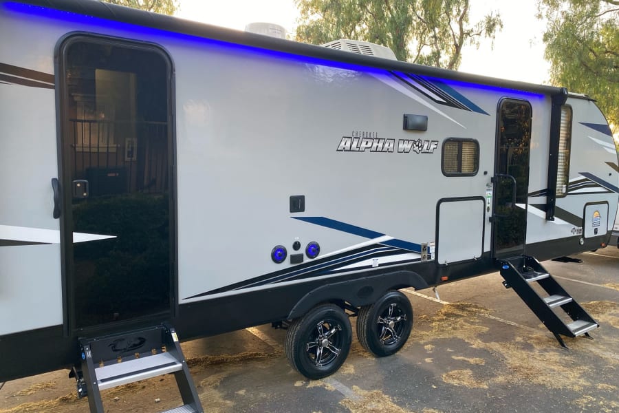 Modern Cherokee Alpha Wolf RV rental with blue LED awning lights and deployable steps, ready for adventure.