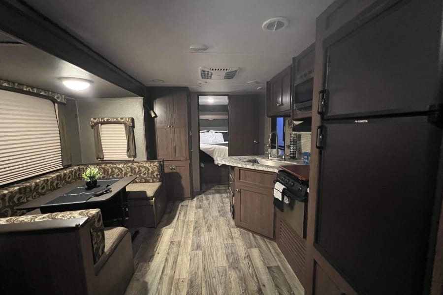 Spacious RV rental interior with a cozy dinette, equipped kitchen, and comfortable bedroom for road trips and adventures.