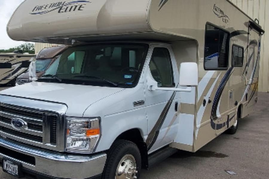 Front view of a white & beige Freedom Elite Class C RV rental. This spacious motorhome is ready for adventure.