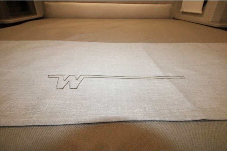 Cozy Winnebago RV rental bed with distinctive logo on the linen, ready for comfortable travel accommodations.