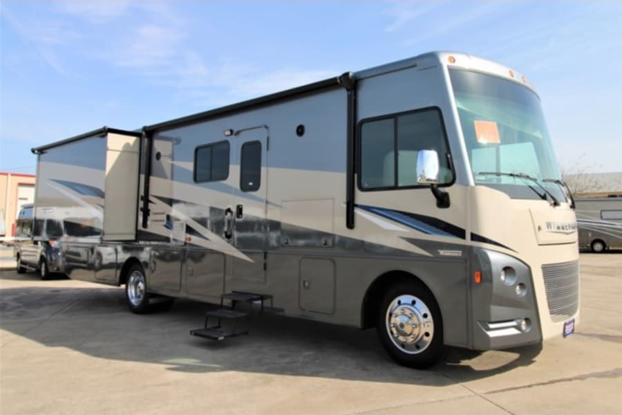 Spacious grey and beige motorhome with slides out and steps down, perfect for your next RV rental adventure.
