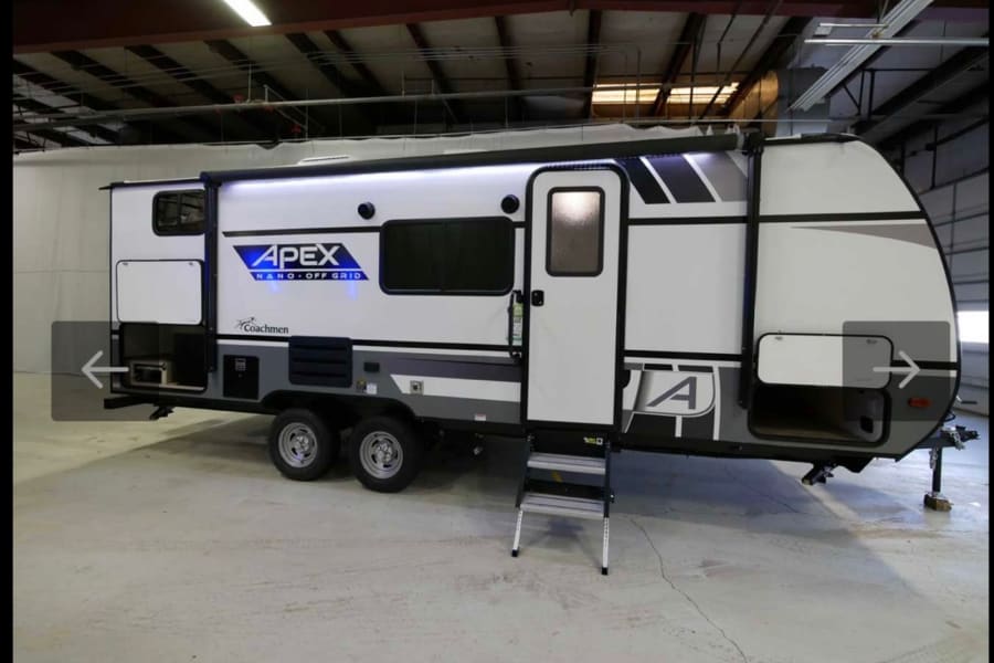 White Apex Nano Off-Grid travel trailer, perfect for your next RV rental. Features illuminated awning, steps & storage, ideal for camping.