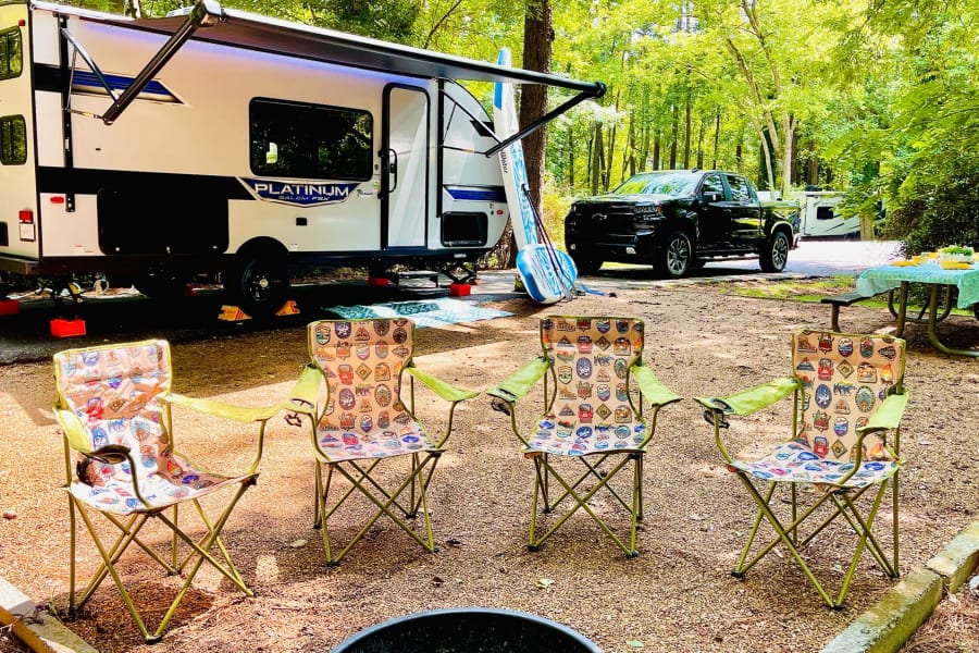 Enjoying the outdoors with an rv rental! A spacious campsite features an RV, truck, chairs, and picnic table.