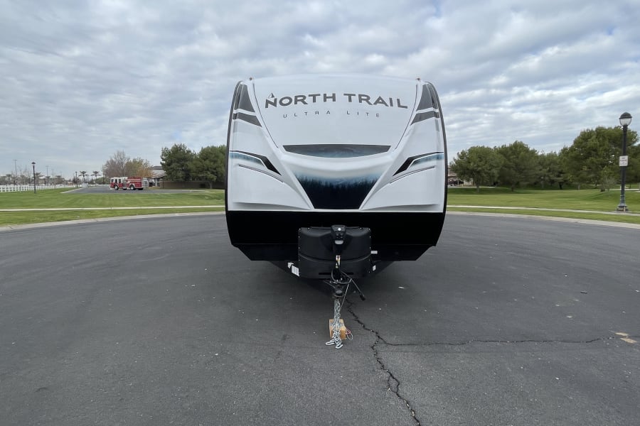 White North Trail Ultra Lite travel trailer, front view, parked on asphalt. Ideal for an RV rental adventure.