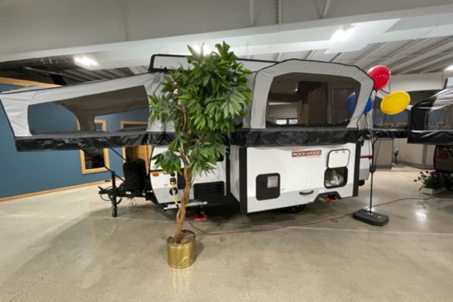 White and gray Rockwood pop-up RV rental fully extended indoors, showcasing its camping setup with two bed areas.