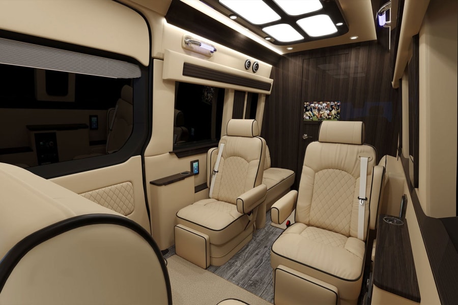 Spacious RV rental interior: luxurious beige leather seats, dark wood trim, ample lighting, and an entertainment screen for comfort.