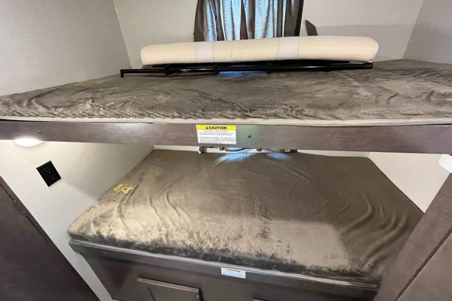 RV rental interior showing cozy bunk beds with a safety rail, perfect for comfortable travel accommodations.