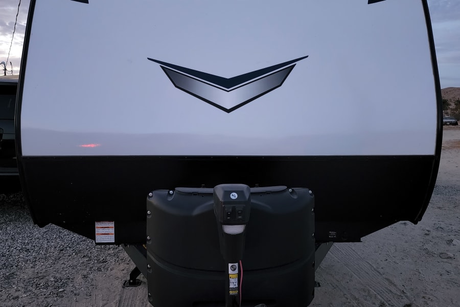 Front view of a sleek, white Bullet Crossfire travel trailer, ideal for your next rv rental adventure, showing its hitch and tanks.