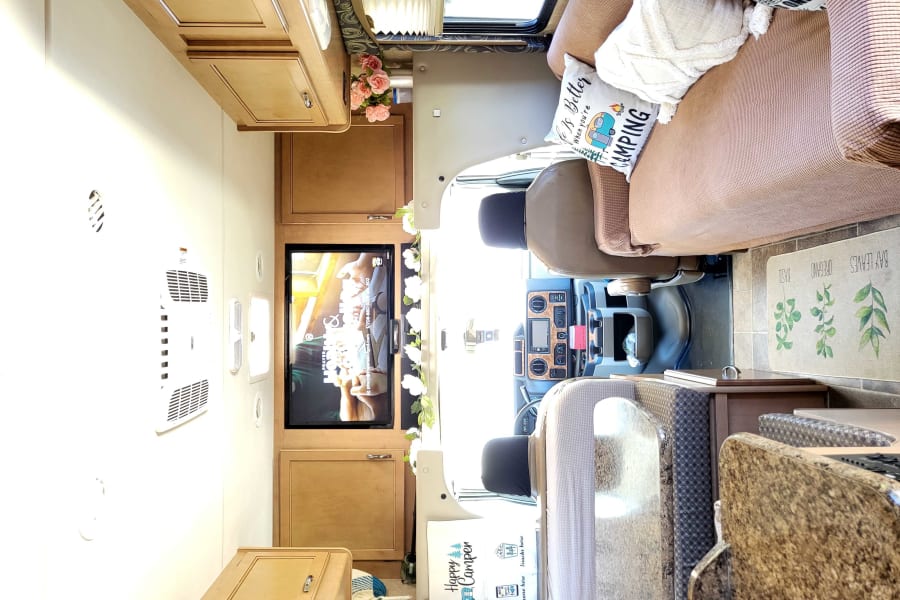 Experience comfort in this RV rental's inviting interior, featuring a cozy living area, kitchen, and driver's cabin.