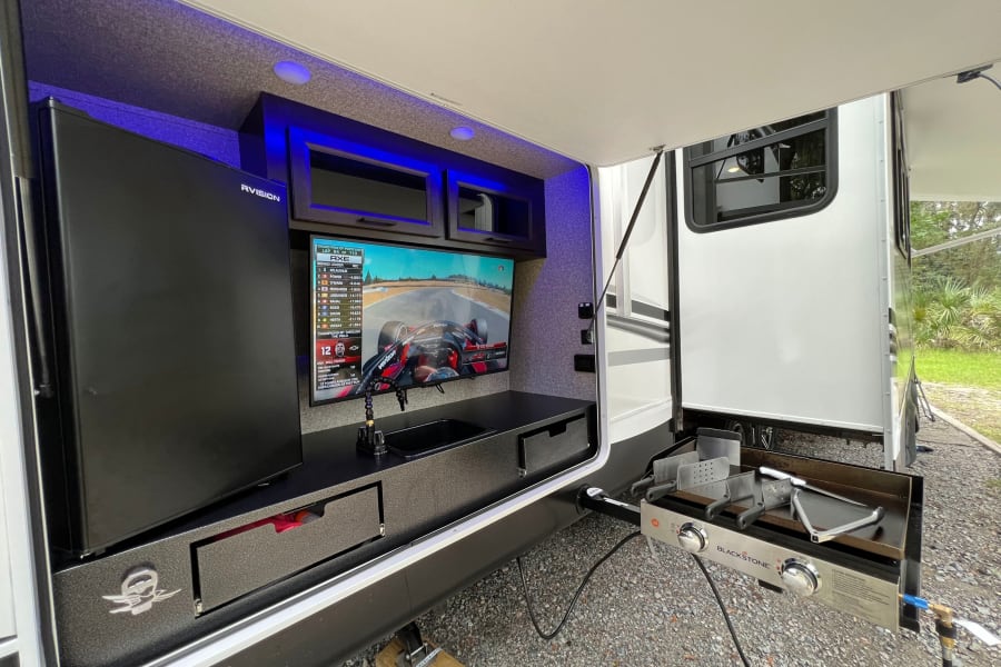 Exterior cooking space equipped with a 22" blackstone Griddle, Sink w/ hot/cold water 42" tv & Fridge to keep the beverages cold. 
