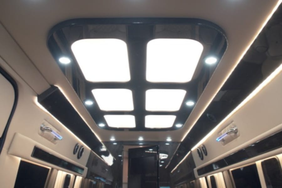 Inside a high-end RV rental, the ceiling features large, bright square LED panels and strip lighting, creating a modern, luxurious interior.