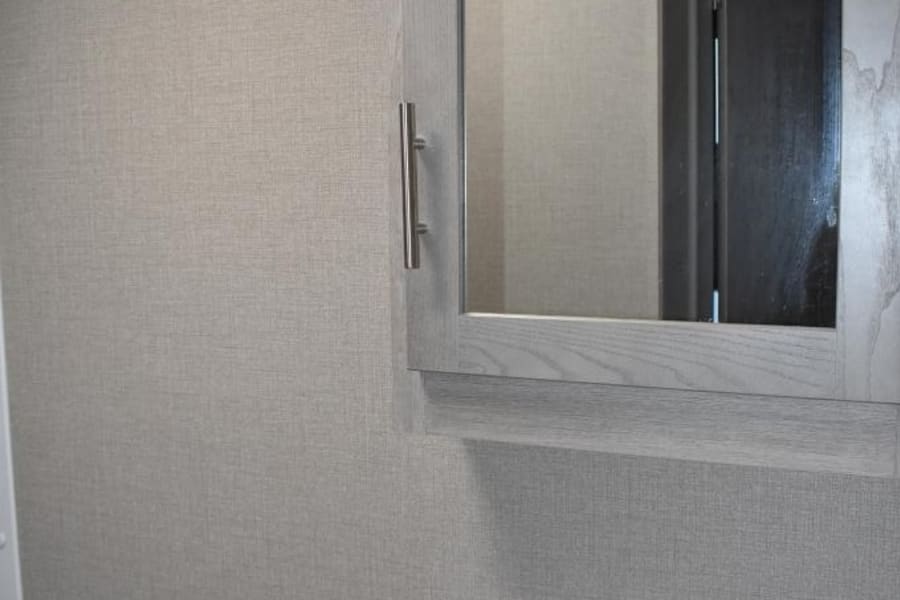 RV rental bathroom showing compact sink, counter, light grey textured walls, and mirrored cabinet.