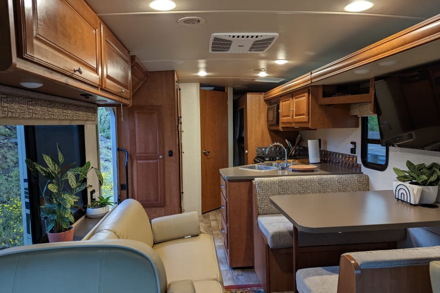Spacious RV rental interior with a cozy sofa, well-equipped kitchen, and dining area, perfect for travel adventures.