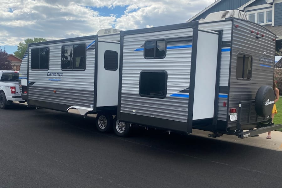 This large Catalina travel trailer with extended slide-outs, hitched to a truck, is ready for an RV rental adventure.