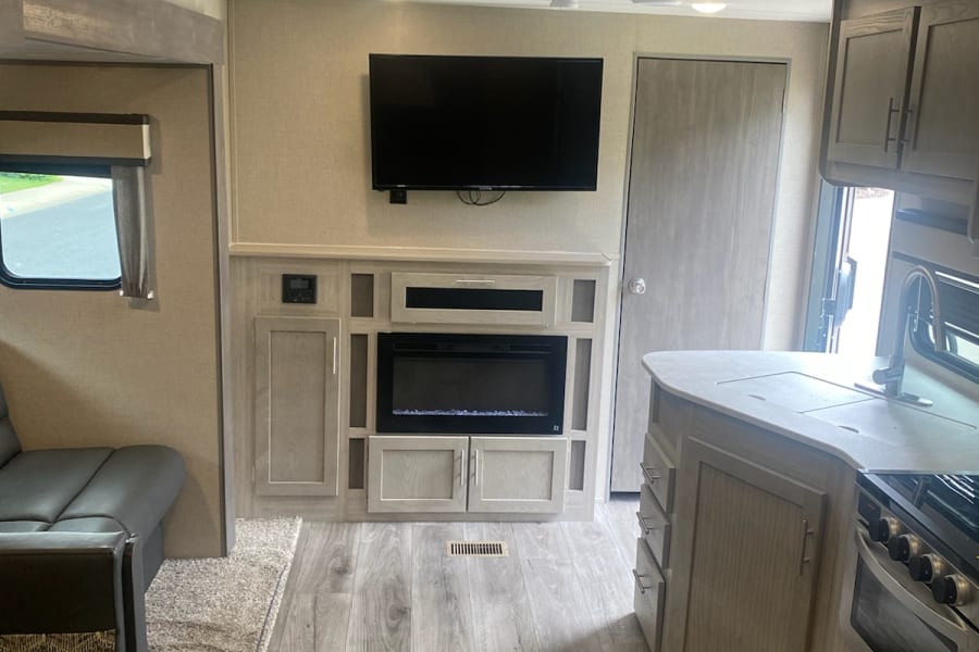 Modern RV rental interior: spacious living area with TV, fireplace, and full kitchen.