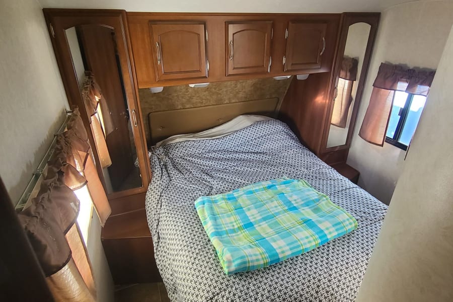 Compact rv rental bedroom with a cozy bed, ample storage, and bedside windows.