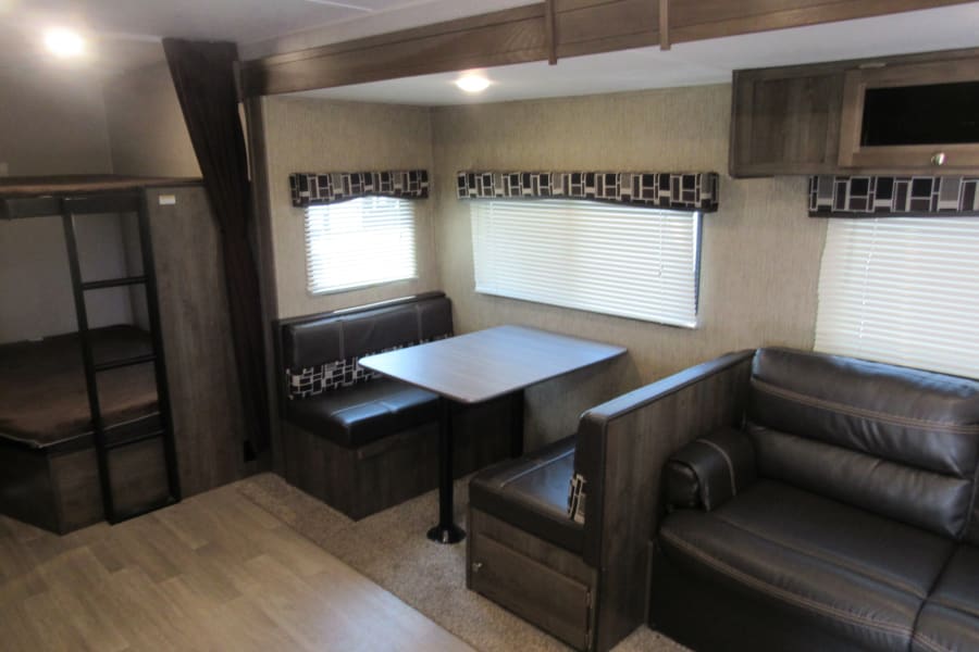 RV rental interior: a practical layout featuring bunk beds, a dinette, and a comfortable sofa.