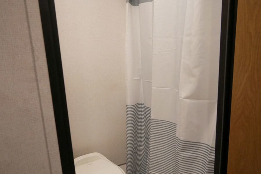 RV rental's compact bathroom with a white toilet and a stylish striped shower curtain.