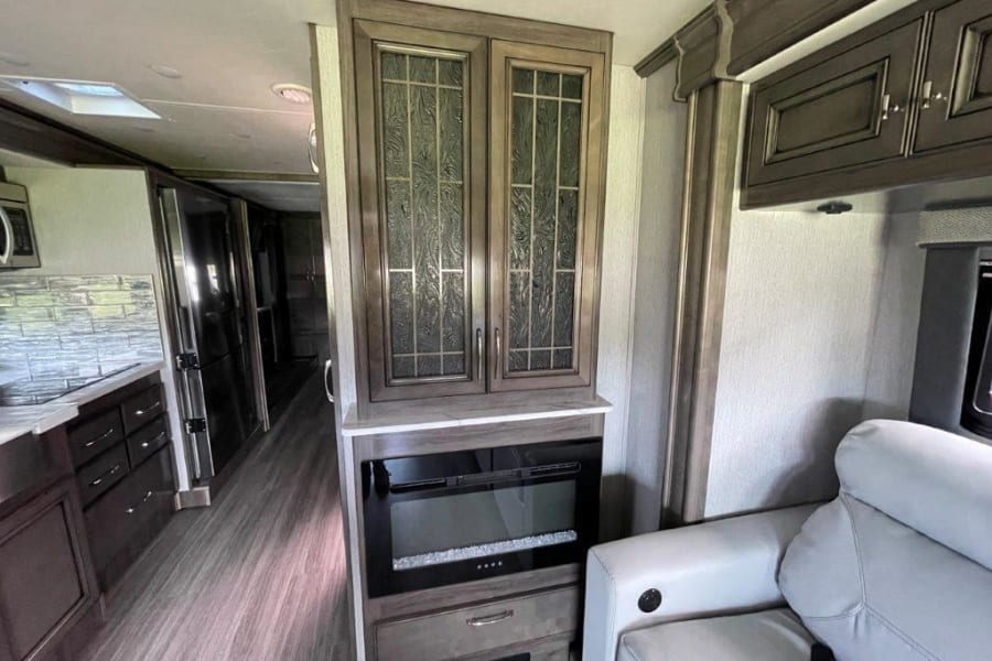 Modern RV rental living area with sofa, fireplace, and sleek kitchen. Ideal for comfortable travel adventures.