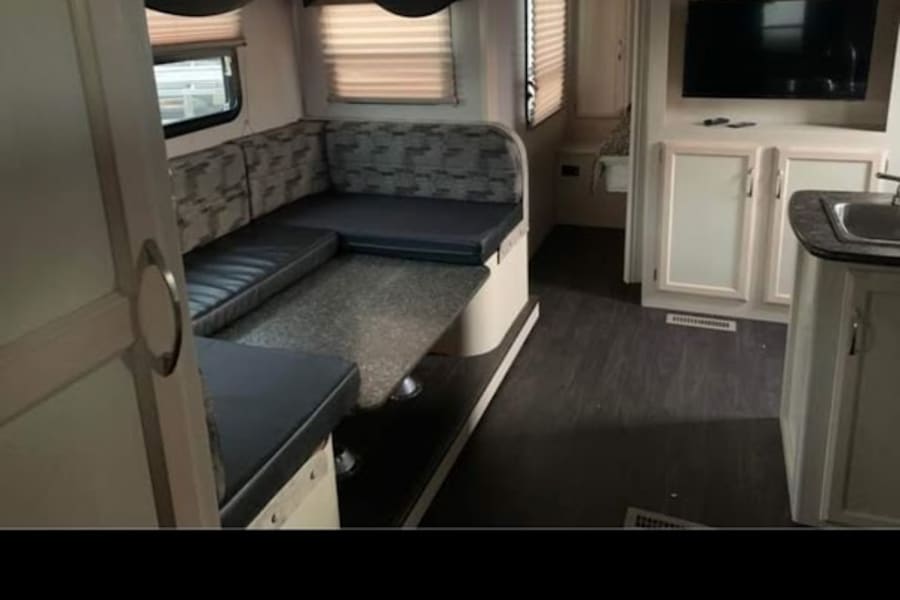 Spacious RV rental interior featuring a comfortable U-shaped dinette, kitchen, and entertainment area. Perfect for your next adventure!