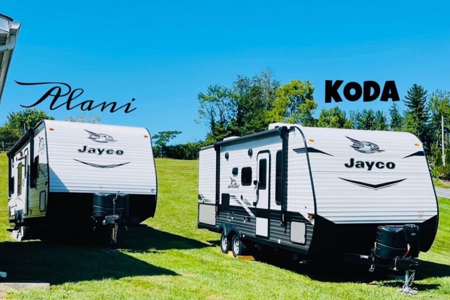 Two Jayco travel trailers, "Alani" and "Koda", parked on grass under a clear sky. Perfect for your next RV rental adventure!
