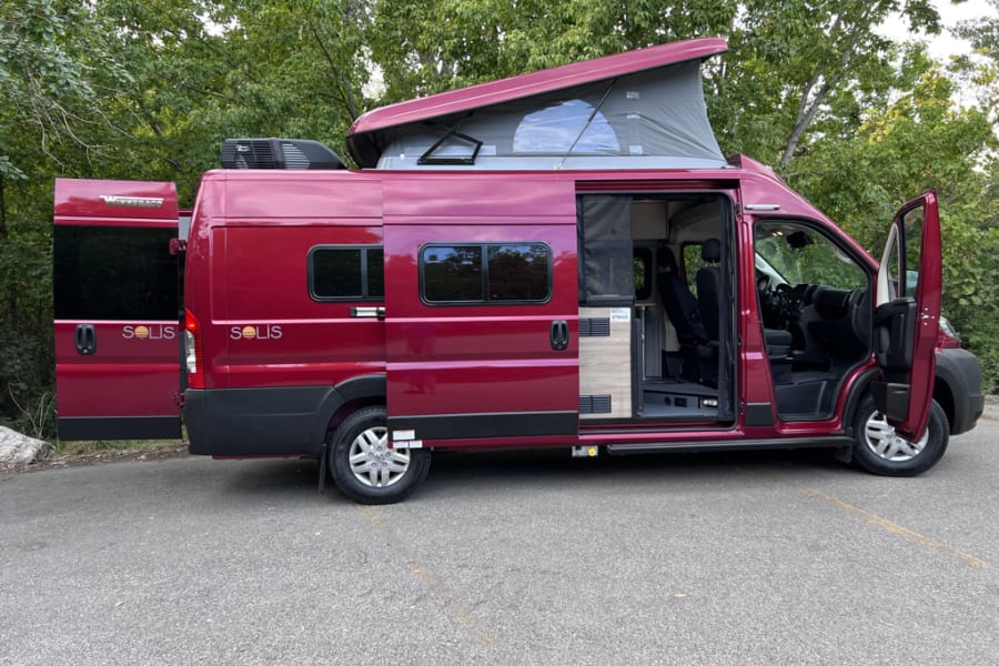 Red Winnebago Solis camper van for rv rental, with pop-top open, ready for adventure.