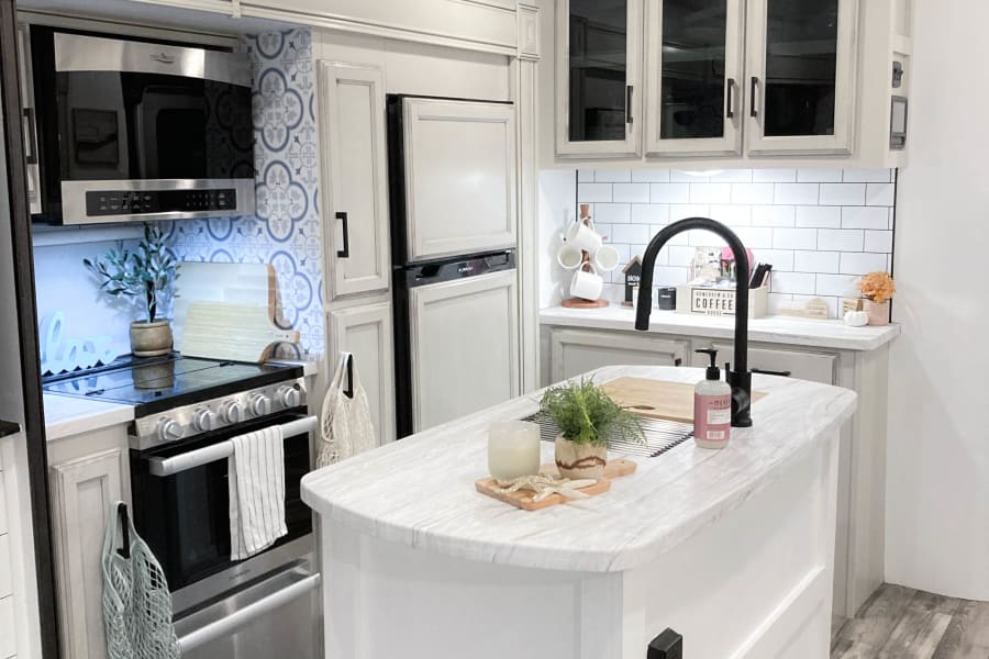Modern and bright RV rental kitchen, featuring white cabinets, subway tile, stainless appliances, and a large island.