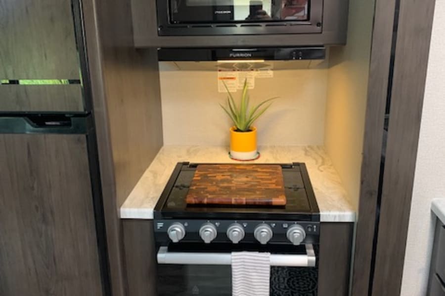 Compact RV rental galley with essential appliances: microwave, stove, and refrigerator. Ideal for on-the-road cooking.
