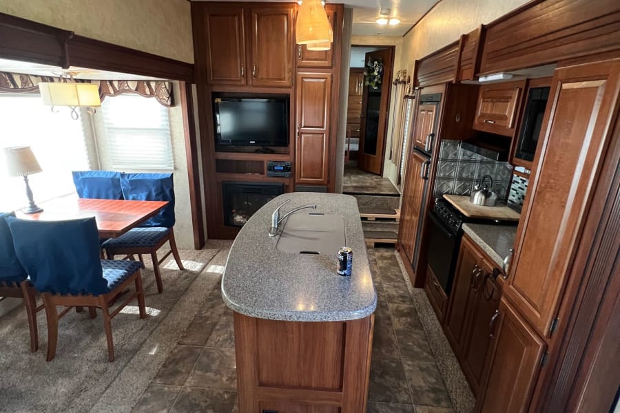Spacious RV rental interior featuring a full kitchen island, dining area, and cozy living space with a fireplace.
