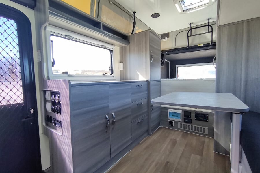 Spacious RV rental interior: a modern kitchen, dinette, and controls for a comfortable trip.