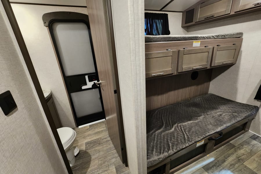 Explore this RV rental's interior: cozy bunk beds & a compact bathroom with toilet.
