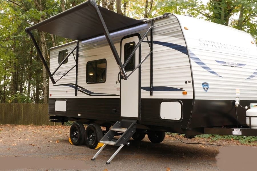 Spacious travel trailer RV rental with extended awning & steps, ready for your outdoor adventures.
