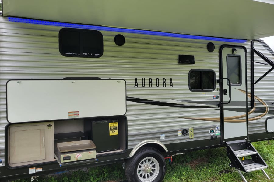 This Aurora travel trailer RV rental offers an outdoor kitchen with grill & fridge, a lighted awning, and sturdy entry steps.