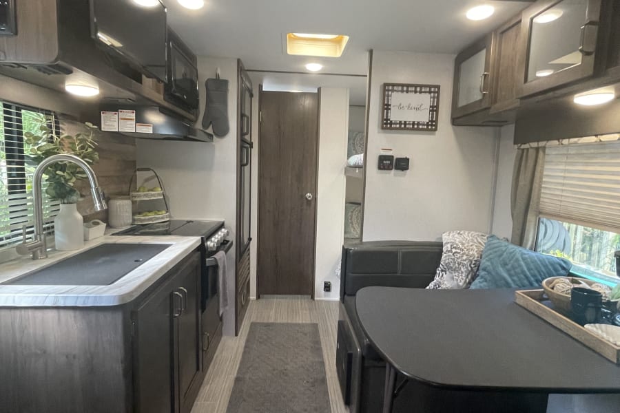 Inside this modern RV rental: a full kitchen, dining booth, and living area. Clean, bright, and ready for your adventure!