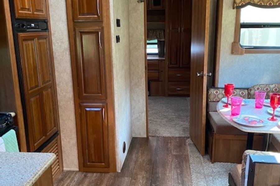 RV rental: inviting interior with a compact kitchen, cozy dinette, and rich wood cabinetry/flooring.
