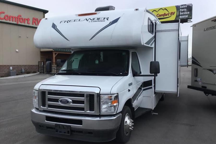 White Coachmen Freelander Class C RV for sale or rv rental at Comfort RV, with slide-outs extended.