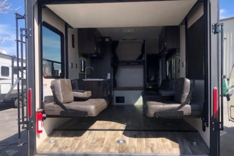 Explore this RV rental's versatile toy hauler interior. Features garage space, fold-down seating, kitchen, and bunk beds.