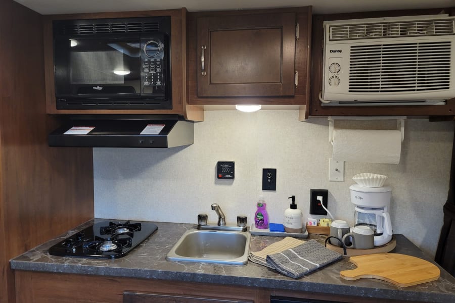 This rv rental kitchen offers a microwave, stove, sink, coffee maker, and wall-mounted AC for comfortable travel.