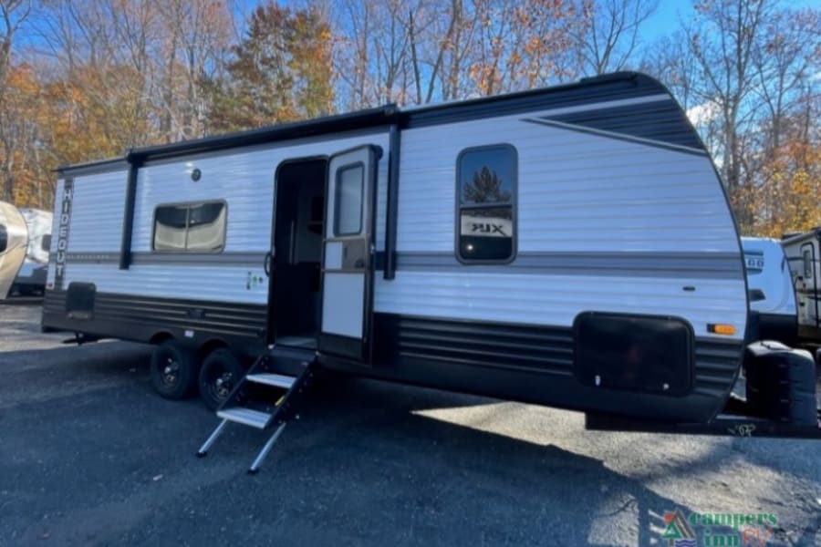 This grey Hideout travel trailer, perfect for an rv rental, is shown with its door open and steps extended.
