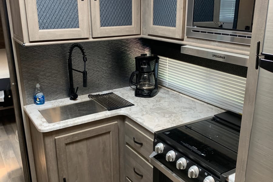 Modern RV rental kitchen with sleek appliances, ample storage, and full cooking setup.