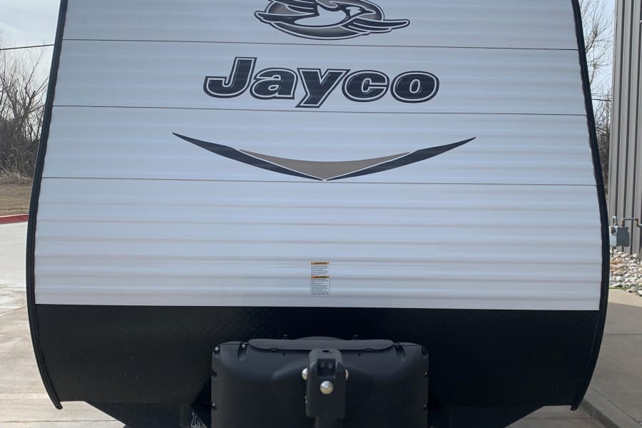 Front view of a white Jayco travel trailer, ready for your next RV rental. Stabilizing jacks are visible below.