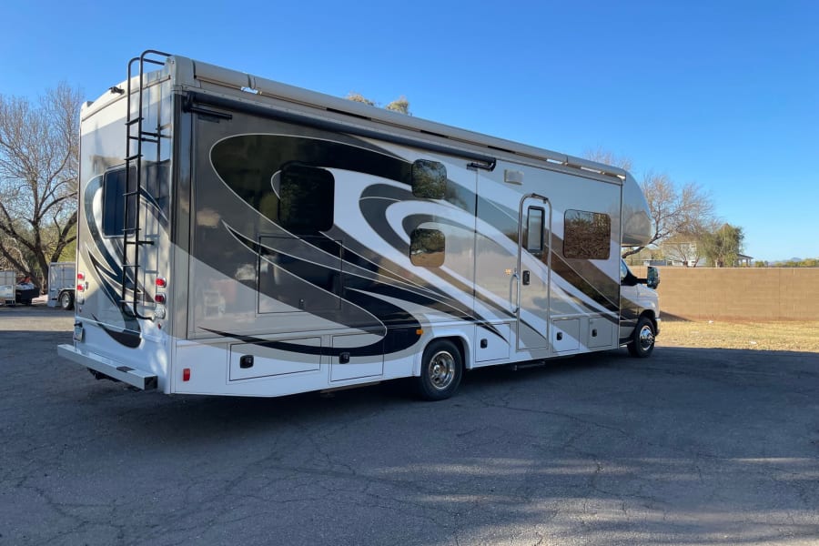 Experience freedom with this beautiful RV rental. A large motorhome, visible parked on asphalt under clear skies.