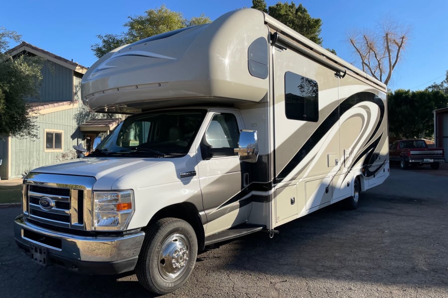Spacious white and tan Class C RV rental parked outdoors, ideal for your next travel adventure.
