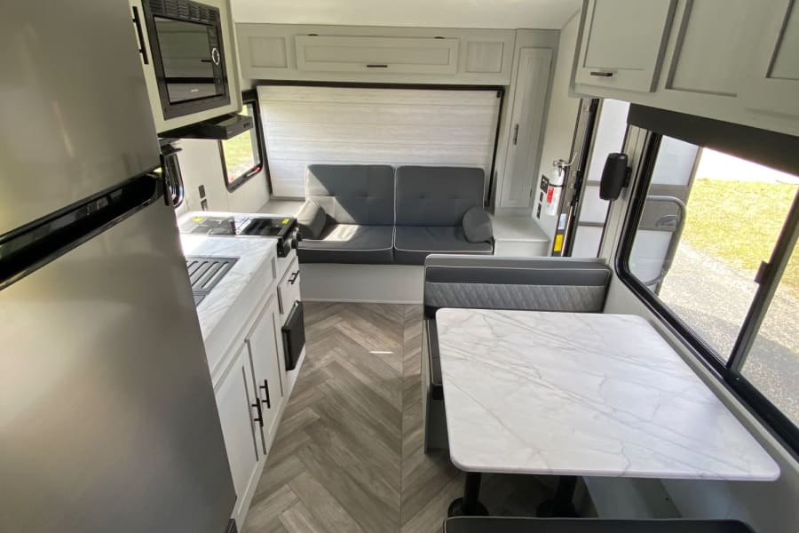 This RV rental interior features a modern kitchen, convertible sofa, and dinette. Bright, clean, and ready for your adventures.