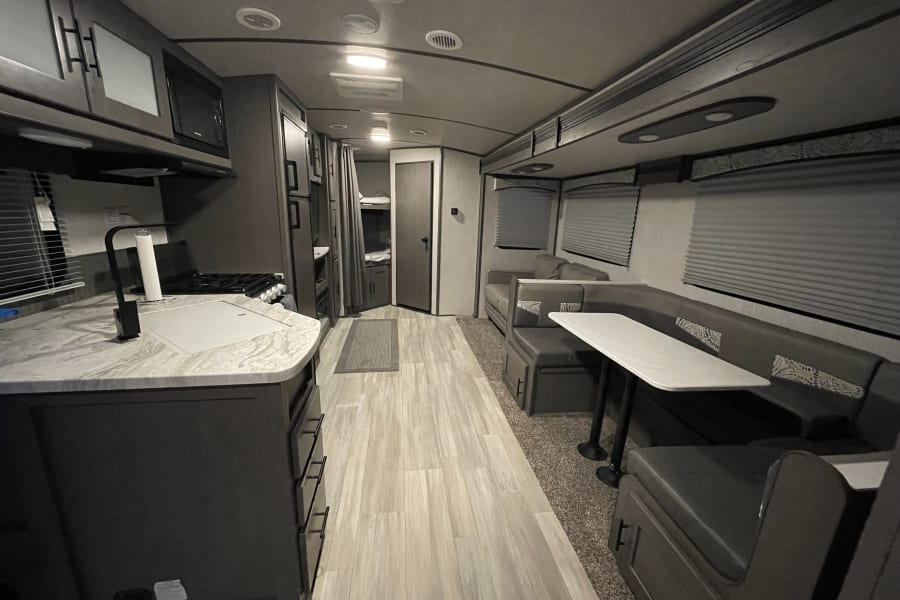 Modern rv rental interior showing kitchen, dining area, and bunk beds, perfect for family adventures.