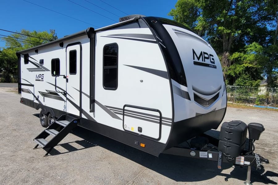 Modern white MPG travel trailer, perfect for an RV rental. Parked outdoors, ready for your next adventure.