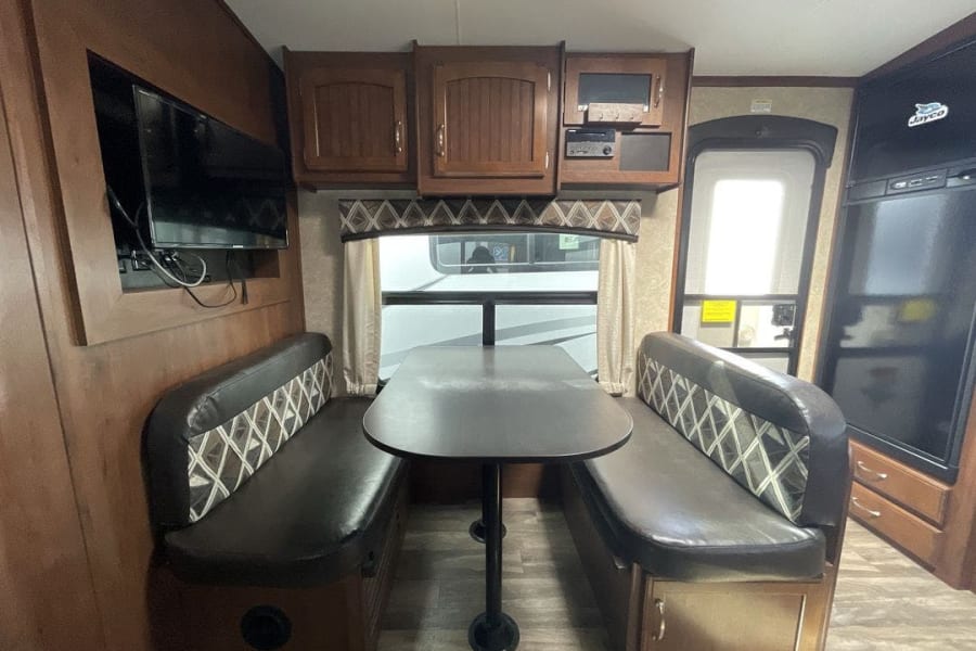 RV rental interior: cozy dinette with TV & kitchen area. Perfect for travel.