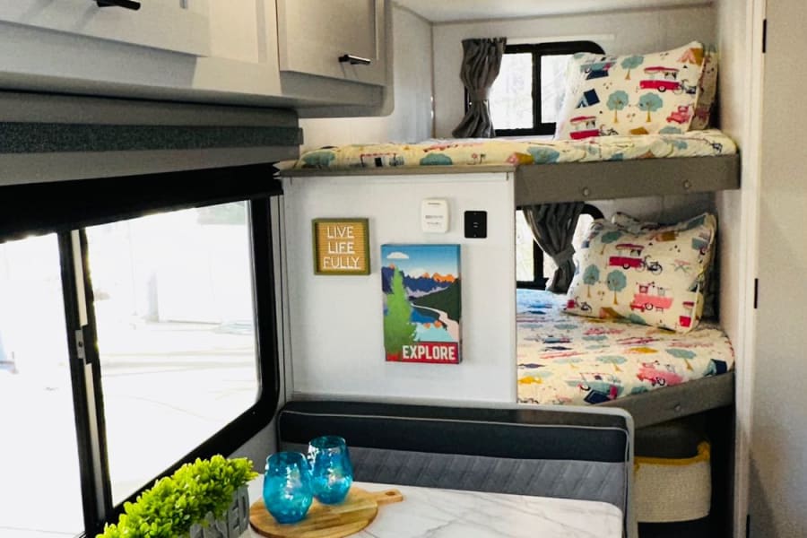 RV rental interior with a cozy dinette, modern cabinets, and comfy bunk beds, great for family trips.