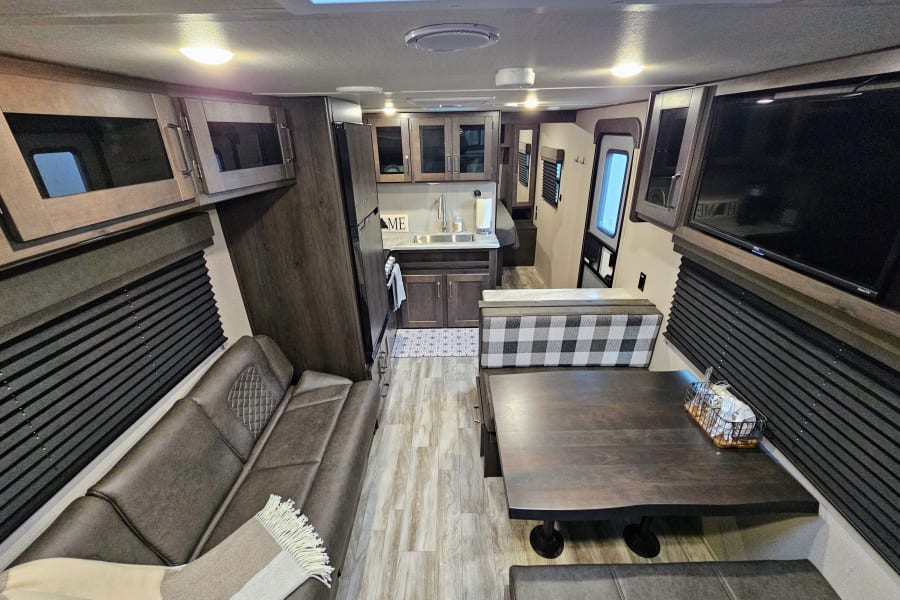 Spacious RV rental interior with modern kitchen, comfy sofa, and dining area.